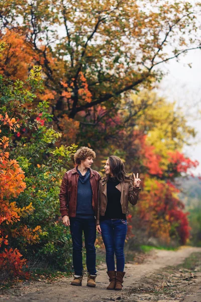 Allegra coppia mostra emozioni. uomo e donna in giacche di pelle e jeans sullo sfondo degli alberi autunnali . — Foto Stock