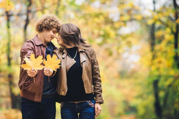 Liebendes glückliches Paar im Herbst im Park mit Herbst-Ahornblättern in den Händen. — Stockfoto