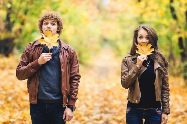 Amare la coppia felice in autunno nel parco con foglie d'acero autunnali in mano . — Foto Stock