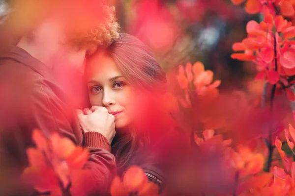 Amour beau couple dans une étreinte tremblante entre les arbres rouges d'automne . — Photo