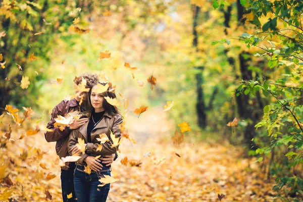 Schöne Herbstallee der Ahorne. Liebendes Paar umarmt sich und gelbe Blätter fallen auf sie. — Stockfoto