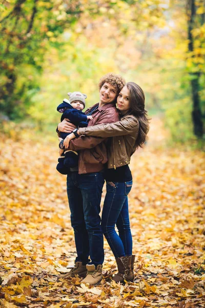 Joven familia feliz abrazo en otoño en el parque . — Foto de Stock