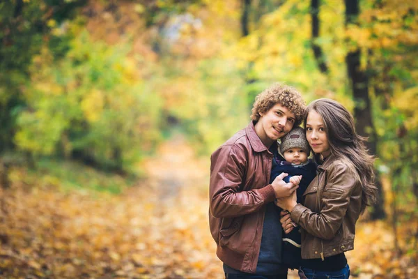 Молодая счастливая семья обнимается осенью в парке . — стоковое фото