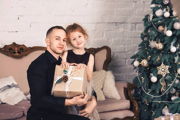 Vader geeft zijn dochter kerstcadeau en omarmt haar. — Stockfoto
