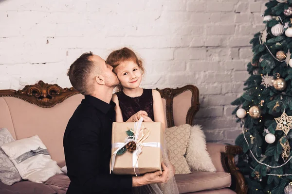 Vader geeft zijn dochter kerstcadeau en kust haar. — Stockfoto