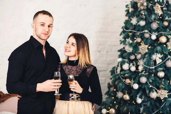 Verliefde paar in stijlvolle kleding met glazen wijn met Kerstmis. — Stockfoto