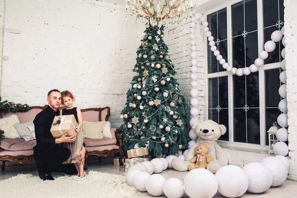 Vader geeft zijn dochter kerstcadeau in ingerichte kamer en omarmt haar. — Stockfoto