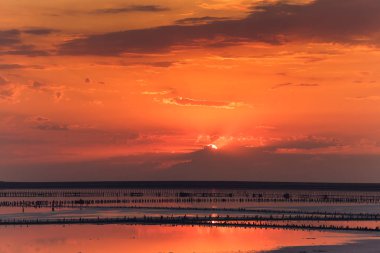 tuz tesisi ahşap yığınları ile göl üzerinde güzel gün batımı.