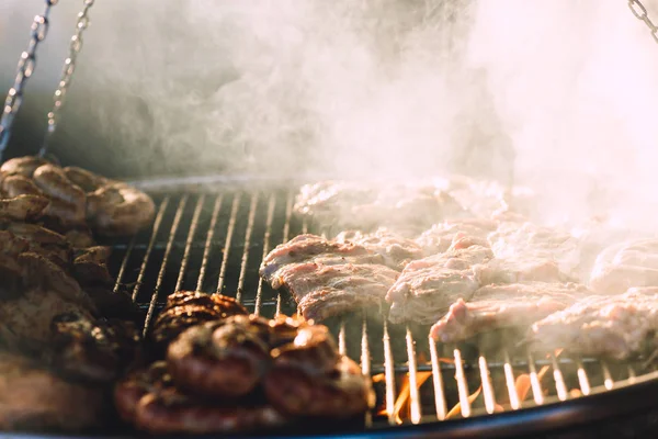 Vlees en worstjes zijn gebakken op grote grill in straat café. — Stockfoto