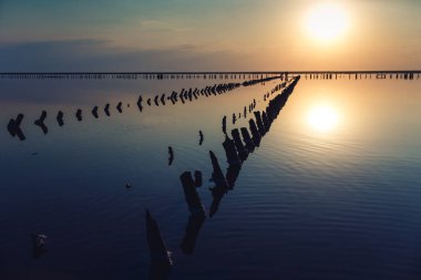 tuz tesisi ahşap yığınları ile göl üzerinde güzel gün batımı.