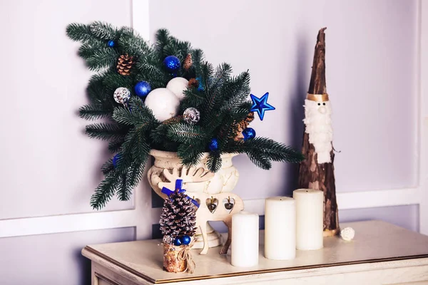 Різдвяна прикраса у вазі, а поруч зі свічкою, олені, дерев'яний Санта . — стокове фото