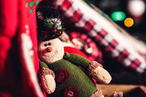 Christmas toy elf sitting on suitcase on background of Christmas tree.