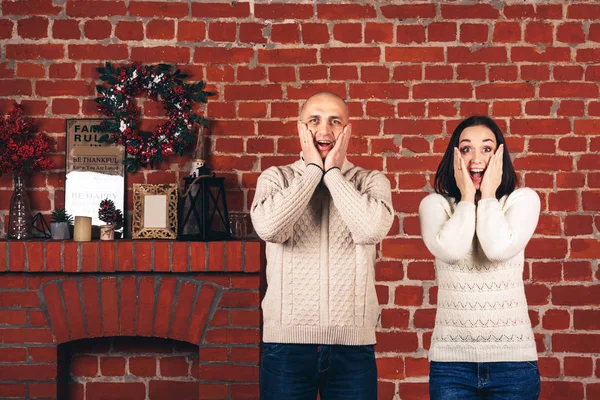 Een vrouw en een man op de achtergrond van een bakstenen muur emoties tonen: wow, schok, ongelooflijk, verrassen. — Stockfoto