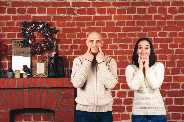 Vrouw en man op een bakstenen muur achtergrond rekken glimlach met hun vingers. — Stockfoto