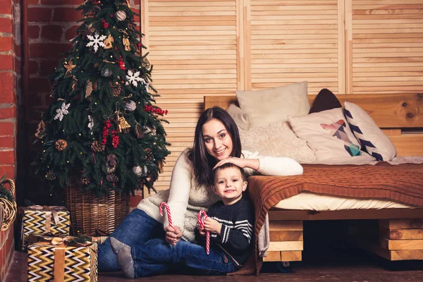 Щаслива мати і син сидять на підлозі і тримають цукеркову тростину . — стокове фото