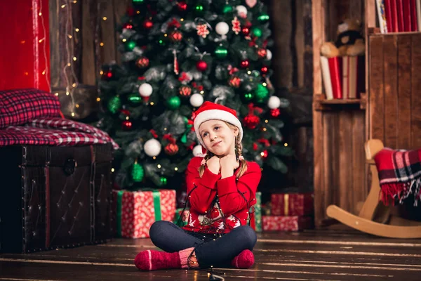 Santa meisje verpakt in garland zittend op de vloer. — Stockfoto