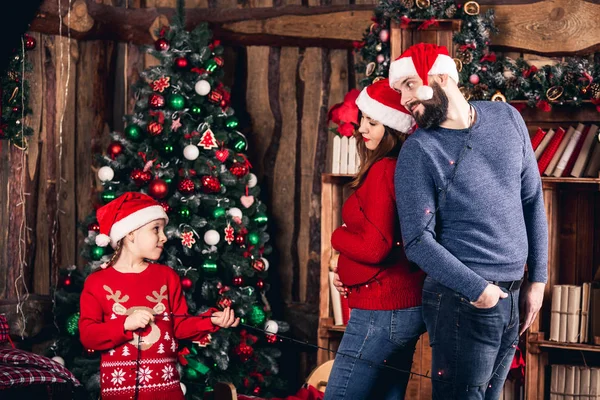 Santa meisje terugloopt vrolijk haar ouders met garland. — Stockfoto