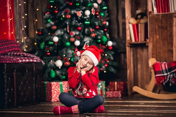 Santa meisje verpakt in garland zittend op de vloer. — Stockfoto