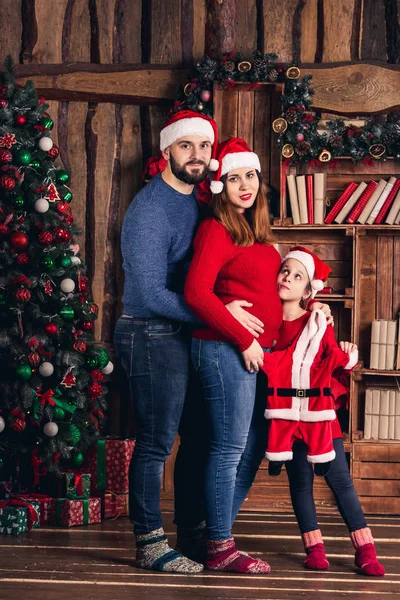 Man, zwangere vrouw en dochter houden een kerst kostuum voor de baby. — Stockfoto