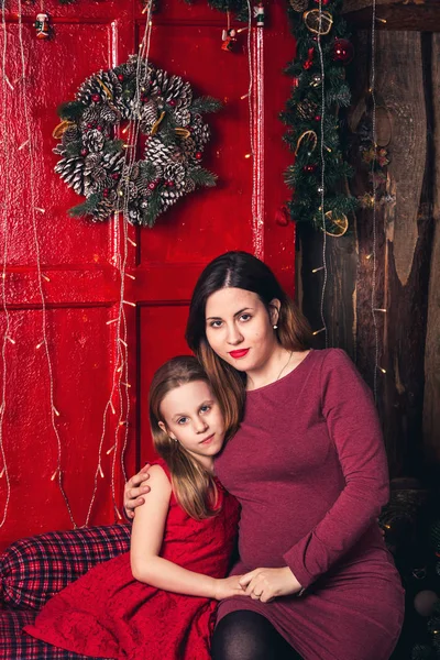 Мати і дочка сидять біля дверей з різдвяним вінком . — стокове фото