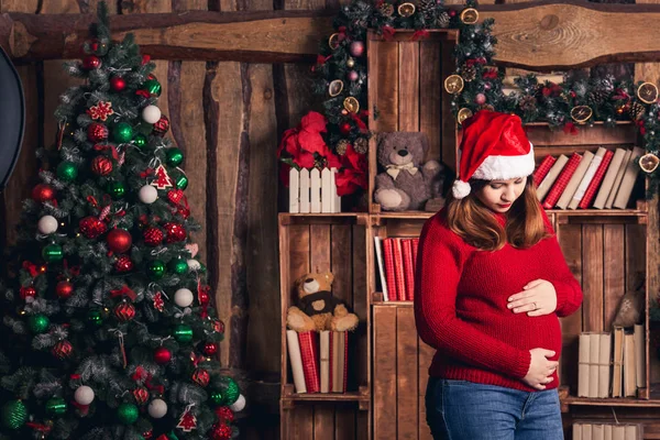 Een zwangere vrouw in een kostuum van Kerstmis is streelde haar buik. — Stockfoto