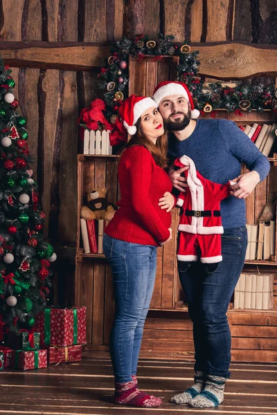 Man en zwangere vrouw houden een kerst kostuum voor de baby. — Stockfoto