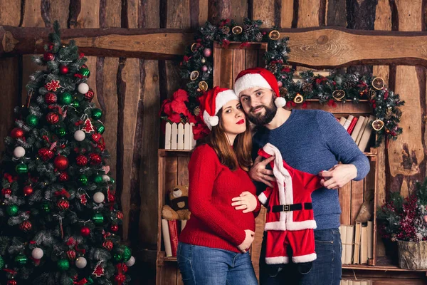 Man en zwangere vrouw houden een kerst kostuum voor de baby. — Stockfoto