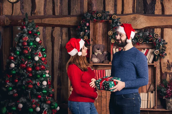 De man geeft een zwanger meisje een kerstcadeau. — Stockfoto