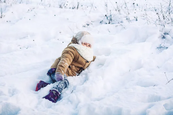 Petite fille drôle couchée en hiver dans la neige. Le concept d'un week-end d'hiver amusant . — Photo