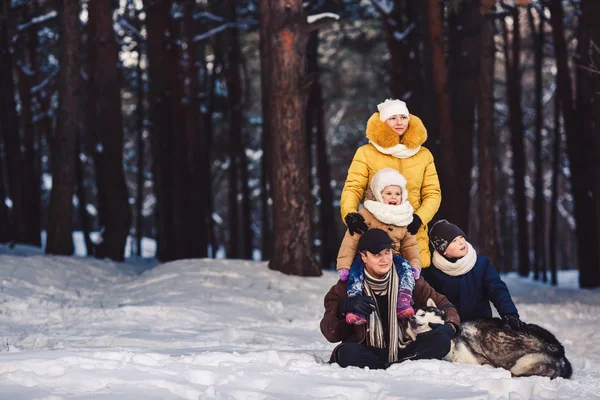 Happy european young family with big dog posing against winter pine forest — Stock Photo, Image