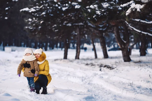 美丽的年轻母亲和她的小女儿在冬天的森林里拥抱. — 图库照片