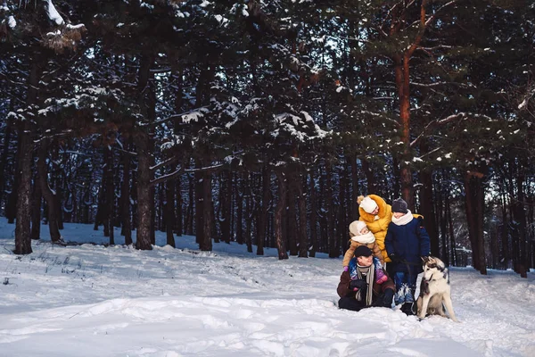Feliz familia joven europea con gran perro posando contra el bosque de pinos de invierno —  Fotos de Stock