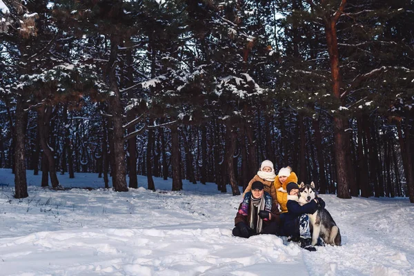 Feliz familia joven europea con gran perro posando contra el bosque de pinos de invierno —  Fotos de Stock