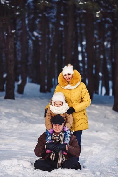 Happy young European family posing in the winter against the backdrop of a pine forest — Stock Photo, Image