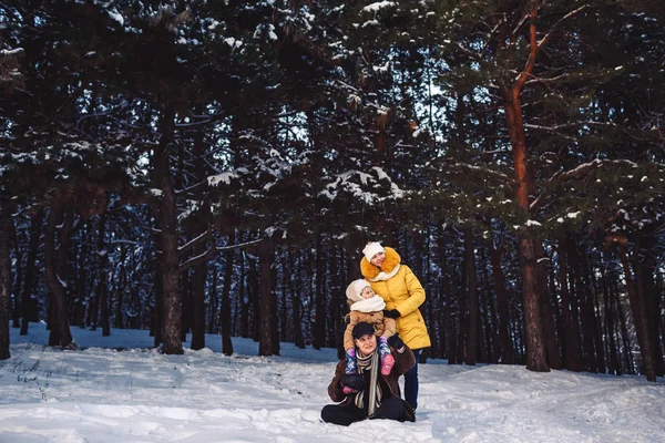 Gelukkige jonge Europese familie poseren in de winter tegen de achtergrond van een dennenbos — Stockfoto