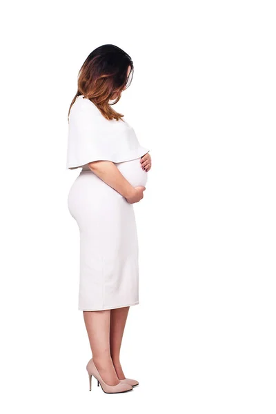 Беременная женщина в белом платье стоит боком и держит живот. Беременная деловая женщина в белом платье. Изолированные на белом . — стоковое фото