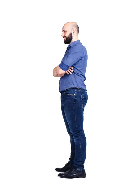 En ung skäggig kille står i sidled och tittar ner. Isolerad på vit. — Stockfoto