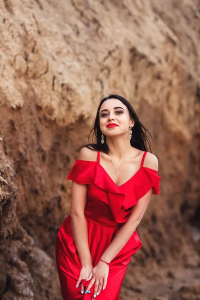 Bela mulher em vestido vermelho posando no fundo do penhasco de argila . — Fotografia de Stock