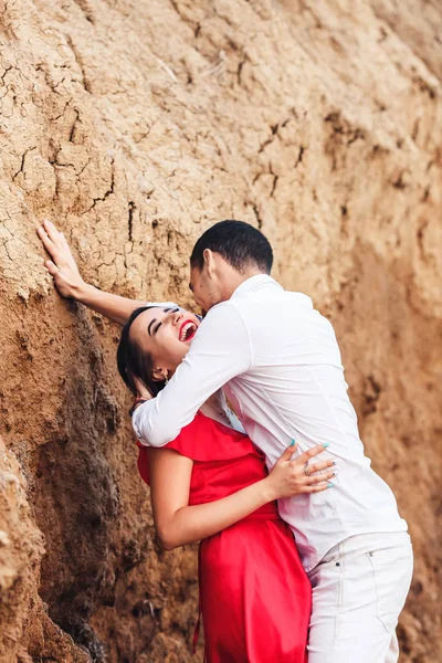 Bela mulher e barbudo homem abraçando perto de argila rock . — Fotografia de Stock