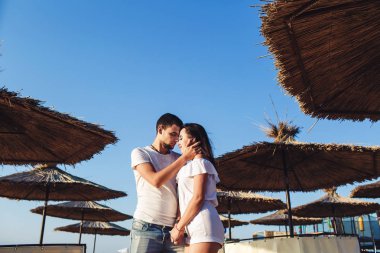 reed şemsiye deniz sahilde arasında sarılma aşık genç çift.
