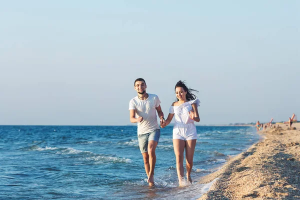Hombre y mujer corren felices a lo largo de la costa del mar . — Foto de Stock
