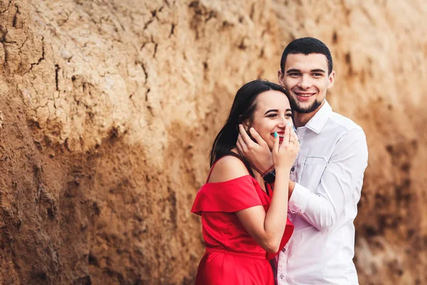 Mooie vrouw en bebaarde man knuffelen in de buurt van klei rock. — Stockfoto