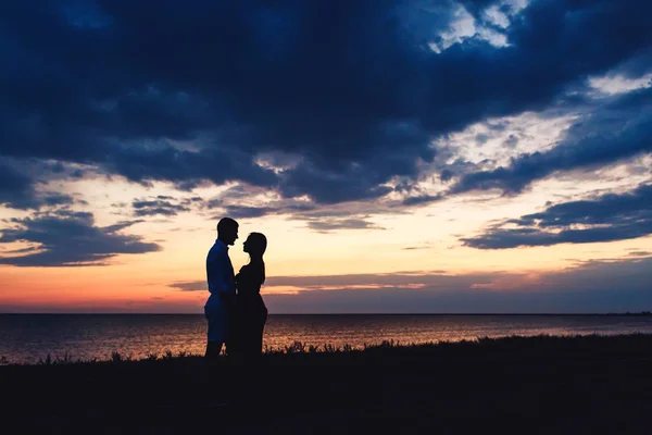 Foto silhouette di una coppia innamorata sullo sfondo di un bellissimo cielo al tramonto e mare . — Foto Stock