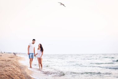 aşık genç çift eğlenceli sahilde yürüyüş ve gülüyor.