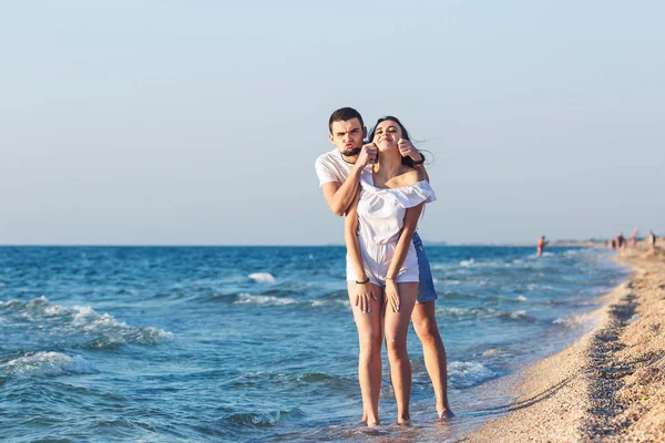 Jeune couple faire un visage et avoir du plaisir sur la plage . — Photo
