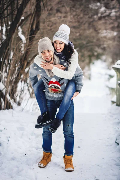 美丽的年轻女孩乐趣搭载男友在冬天在公园. — 图库照片