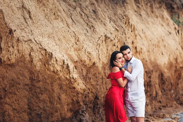 Bela mulher e barbudo homem abraçando perto de argila rock . — Fotografia de Stock