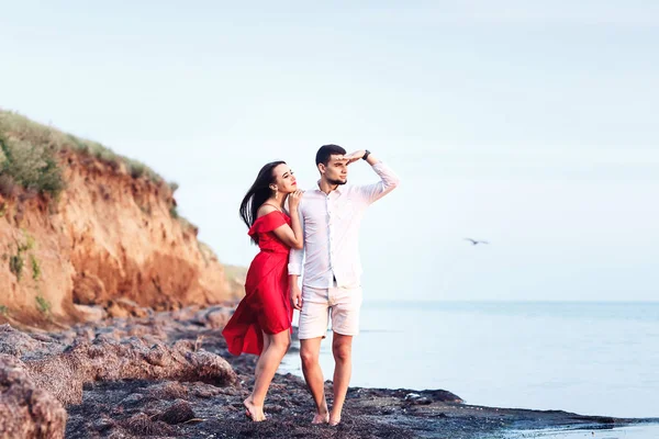 Hombre y chica de pie en una orilla del mar desierta y mirar a la distancia . — Foto de Stock