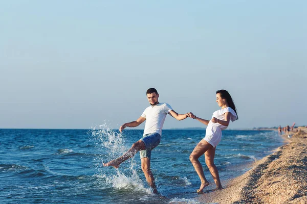 Chico y chica diversión salpicaduras en el mar . — Foto de Stock