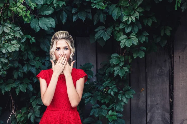 Muestra conmoción, miedo. atractiva joven rubia en un vestido rojo cubre su boca con sorpresa . — Foto de Stock